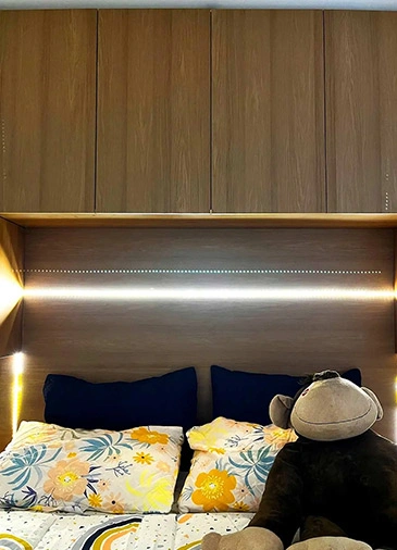 Cama de casal com bicho de pelucia, armários superiores e iluminação embutida de LED.